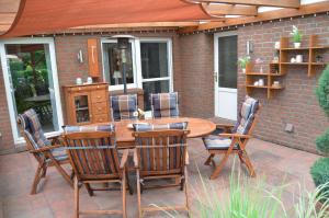 een patio met een houten tafel en stoelen bij Ferienhaus Nikki 35528 in Uplengen