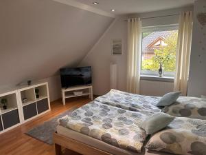 a bedroom with two beds and a television at Ferienhaus Nikki 35528 in Uplengen