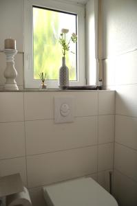a bathroom with a toilet and a window with flowers at Ferienhaus Nikki 35528 in Uplengen +59 photos