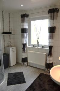 a bathroom with black and white curtains and a window at Ferienhaus Nikki 35528 in Uplengen