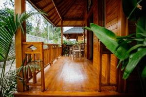 Angseri Villas في تابانان: مدخل منزل خشبي مع طاولة وكراسي