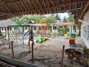 un parque infantil frente a una casa en Oluwa Seun Beach Cottages, Mtwapa, en Mombasa