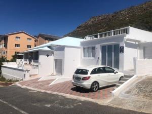 a white car parked in front of a white house at Blue Bay Studio Bayview in Cape Town