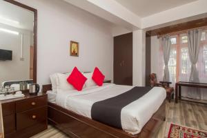 a bedroom with a large bed with red pillows at Capital O 66317 Hotel La Terrasse in Gangtok