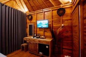 Habitación con TV en una pared de madera. en Angseri Villas en Tabanan