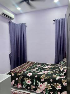 a bedroom with a bed with a floral comforter at Sheri homestay in Kuala Nerang