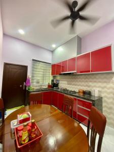 cocina con armarios rojos y ventilador de techo en Sheri homestay, en Kuala Nerang