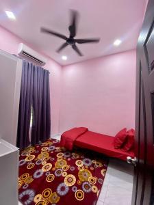 a bedroom with a red bed and a ceiling fan at Sheri homestay in Kuala Nerang