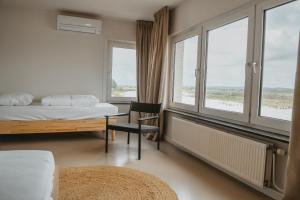 - une chambre avec un lit, un bureau et des fenêtres dans l'établissement Maas Suites - The River House, Maastricht - Lanaken, à Lanaken