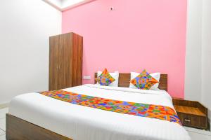 1 dormitorio con 1 cama grande y pared de color rosa en FabExpress Golden Epoch en Indore