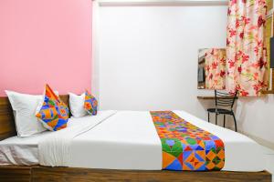 a bedroom with a white bed with colorful pillows at FabExpress Golden Epoch in Indore