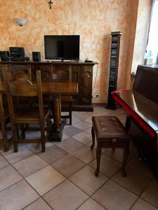 ein Wohnzimmer mit einem TV, einem Tisch und einem Klavier in der Unterkunft Spicchio di Langa - casa indipendente tra le vigne e le Alpi in Belvedere Langhe