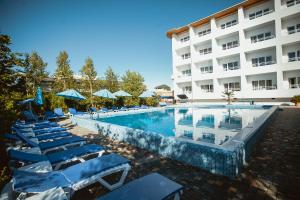 a swimming pool with blue lounge chairs and a hotel at Villa Santorini in Zatoka