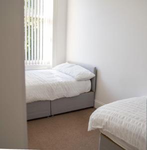 a white bedroom with a bed and a window at Thornhill Apartment in Sunderland