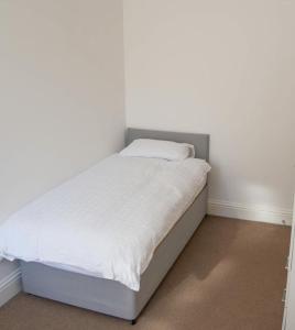 a bed in a room with white sheets and pillows at Thornhill Apartment in Sunderland