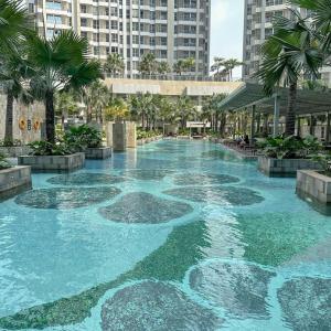 a large pool of blue water with palm trees and buildings at Studio, West Jakarta Oasis, Netflix, Pool, Mall in Jakarta