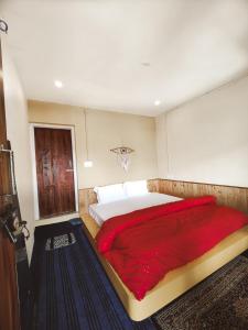 a bedroom with a large bed with a red blanket at Mitra Hostel Sonamarg in Sonāmarg