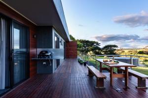 un balcón de una casa con una mesa y una parrilla en Wamoon Retreat - Luxe House, en Yanakie