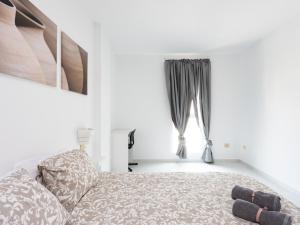 a white bedroom with a bed and a window at Live Medano Mirazul in El Médano
