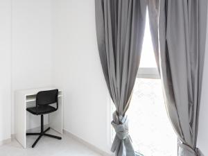 a black chair sitting next to a window with curtains at Live Medano Mirazul in El Médano