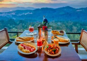 a table with plates of food on it with a view at Sleeping Beauty by Nature Resorts and Stays in Coonoor