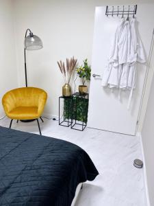 een slaapkamer met een zwart bed en een gele stoel bij WellnessStudioTiel in Tiel