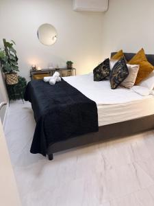 - un grand lit avec une couverture et des oreillers noirs dans l'établissement WellnessStudioTiel, à Norwich
