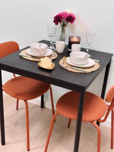 WellnessStudioTiel في تيل: طاولة غرفة طعام سوداء مع كرسيين برتقال وطاولة سوداء
