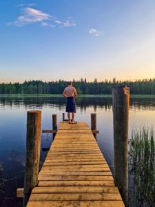 a man standing on a dock on a lake at Glamping Laenlammen tila in Rovaniemi