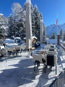 un grupo de mesas y sillas en la nieve en Restaurant Hotel Schermtanne en Adelboden