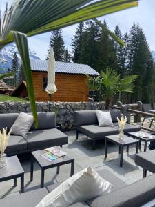 eine Terrasse mit Sofas, Tischen und einer Steinmauer in der Unterkunft Restaurant Hotel Schermtanne in Adelboden