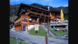 a large wooden building with stairs in front of it at Restaurant Hotel Schermtanne in Adelboden