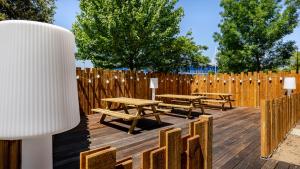 a wooden deck with picnic tables and a fence at Akena Nantes Atlantis Zénith in Saint-Herblain