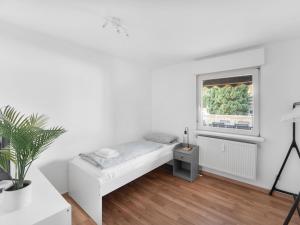 ein weißes Zimmer mit einem Bett und einem Fenster in der Unterkunft Work & Stay in Adelheitsdorf in Adelheidsdorf
