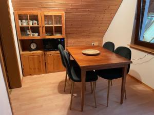 - une table à manger en bois avec des chaises noires dans la cuisine dans l'établissement Haus Tannenzäpfle, à Waldachtal