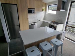 a kitchen with a white counter and stools in it at Linden Lodge Haven in Wellington