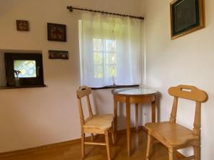 Duas cadeiras e uma mesa num quarto com uma janela em Country House Pri Lipet Žiri em Žiri