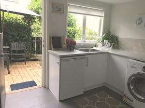 uma cozinha com um lavatório e uma máquina de lavar roupa em Jacaranda House Garden Suite em Brisbane