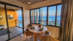 a room with a table and chairs and windows at Penthouse-level Waterfront Apartment in Darwin