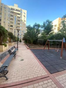 a park with two benches and a playground at RentalSevilla en el barrio de Nervión in Seville