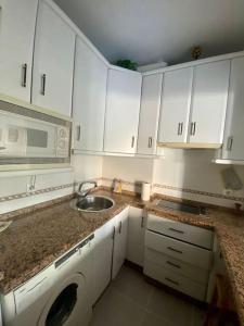 a kitchen with white cabinets and a sink and a microwave at RentalSevilla en el barrio de Nervión in Seville