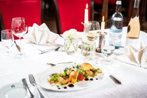 un piatto bianco di cibo su un tavolo con bicchieri da vino di Romantik Hotel Gutshaus Ludorf a Ludorf