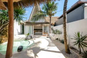 a courtyard with palm trees and a swimming pool at Mahi Mahi Villa & Suites in Uluwatu