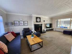 ein Wohnzimmer mit einem Sofa und einem Tisch in der Unterkunft Kennedy Villa - 5 Bed House with Hot Tub in Bicester