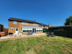 a house with a yard with chairs and tables at Kennedy Villa - 5 Bed House with Hot Tub in Bicester