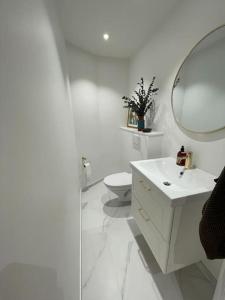 a white bathroom with a sink and a mirror at Nyrenoveret charmerende lejlighed i Odense C! in Odense