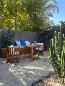 a patio with a wooden table and chairs and cactus at Marie's Byron Getaway in Byron Bay