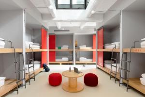 Habitación con literas, mesa y sillas rojas. en Combo Torino, en Turín