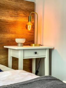 a table with a lamp on it next to a bed at Glam House Apartments in Poznań