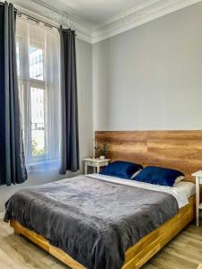 1 dormitorio con 1 cama grande con almohadas azules en Glam House Apartments, en Poznan